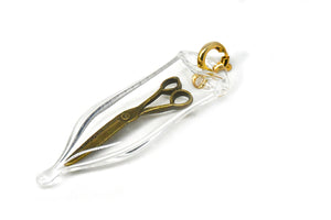 Glass capsule charm with antique brass scissors inside glass